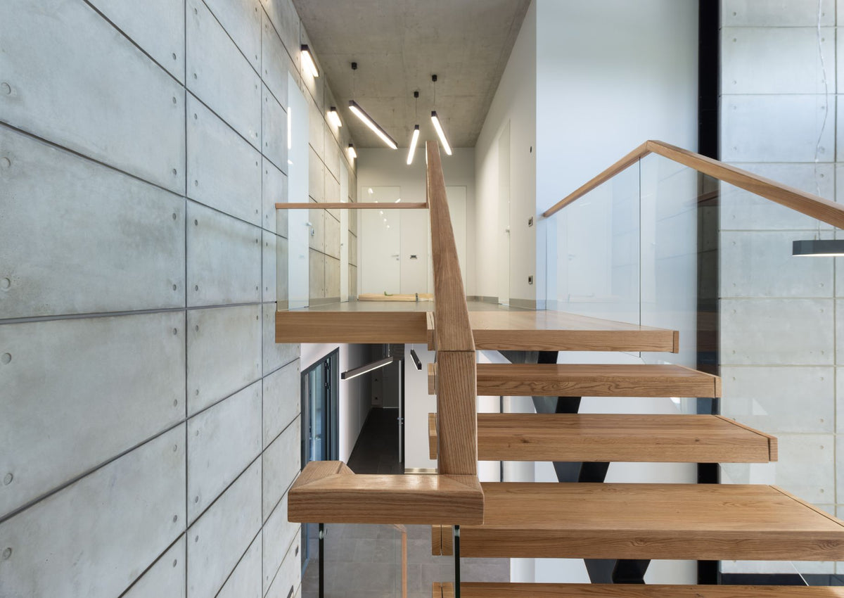 Fragment of interior design of contemporary loft style house with wooden steps with glass fence leading to second floor