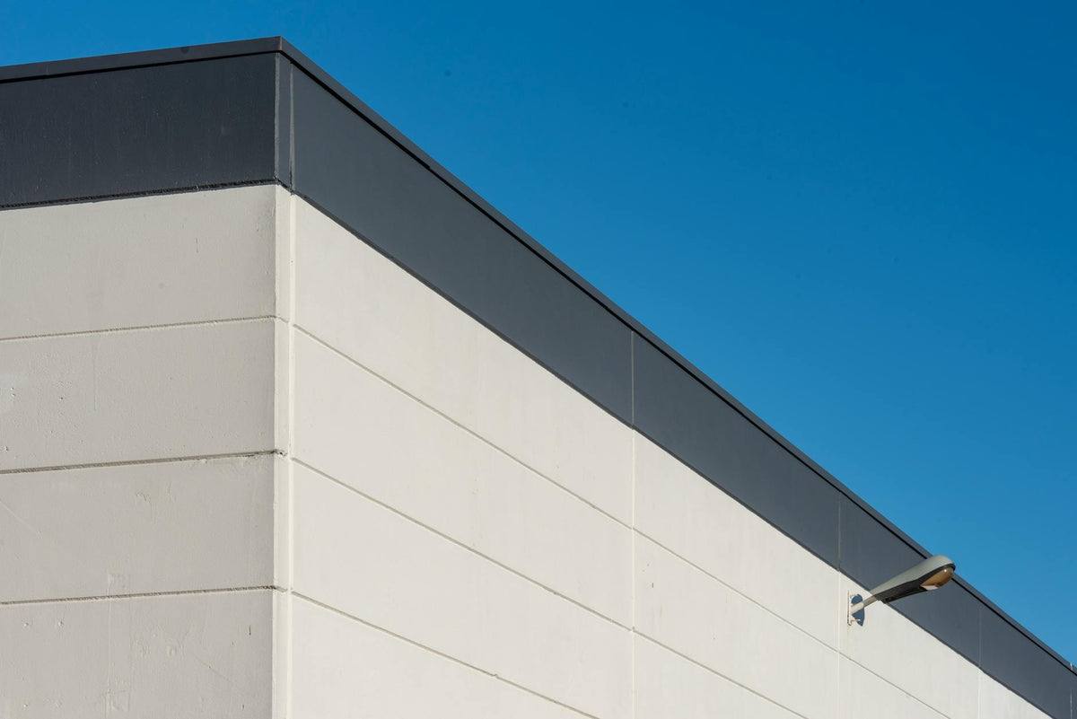 A modern building exterior with minimalist design and a clear blue sky background.
