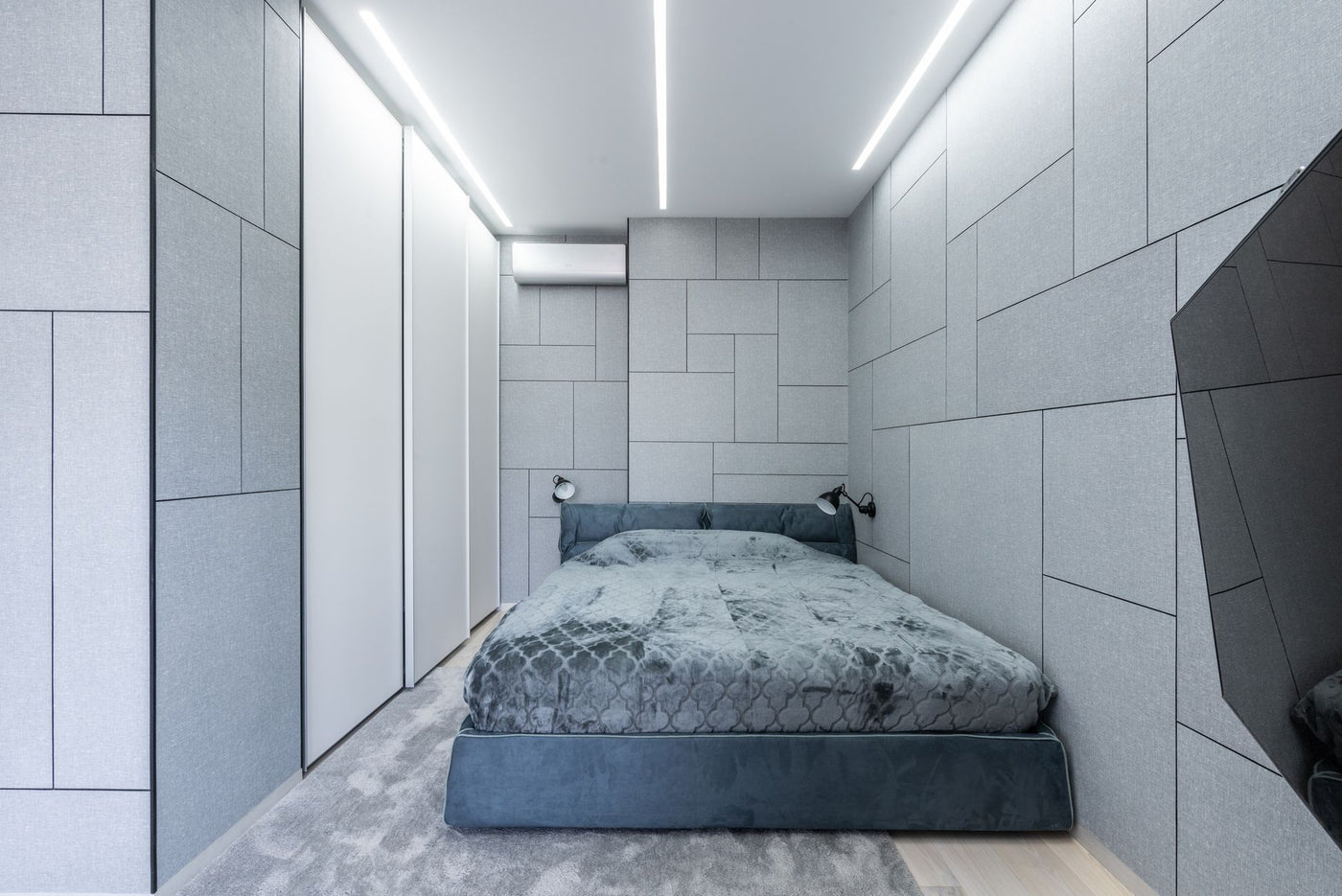 Interior of light modern bedroom with gray bed on carpet near lamps on wall and TV
