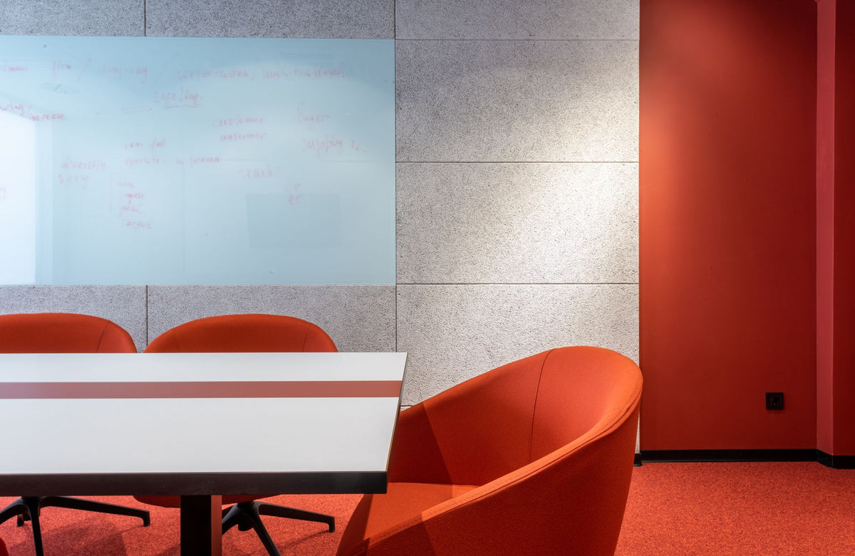 Comfortable orange chairs placed on rug at white table near wall with projection in modern spacious office of business center