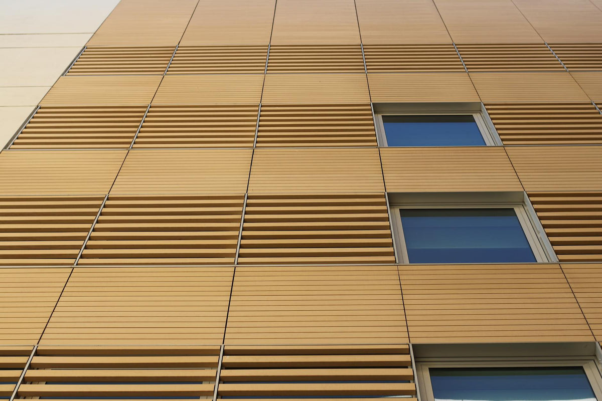 Sleek building facade with wooden slats and windows, showcasing modern architectural style.