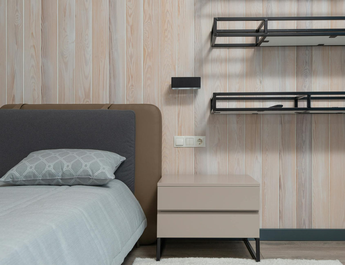 Wooden nightstand and empty shelves near comfortable bed with cushions in modern apartment