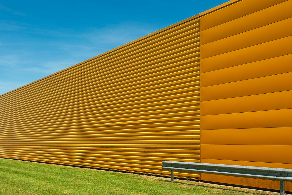 Yellow industrial building facade with clear blue sky, showcasing modern architecture.