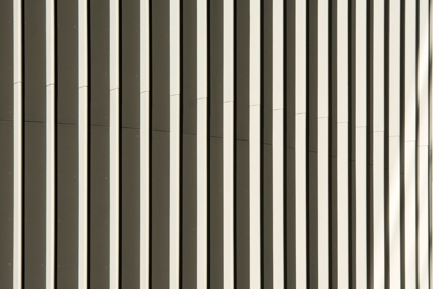 Close-up view of a modern building facade showcasing abstract vertical patterns in neutral tones.