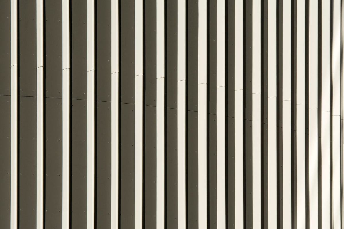 Close-up view of a modern building facade showcasing abstract vertical patterns in neutral tones.